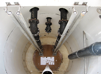 Interior of wet well with risers, still well, drain, and vent piping.